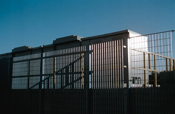 a tall fence with a building in the background
